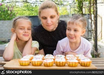 Mother and two daughters salivate looking at freshly Easter cupcakes