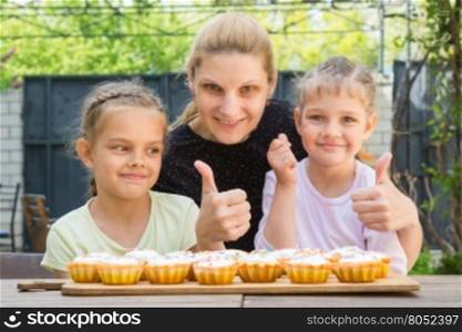 Mother and two daughters show a thumbs-up, and dress easter cupcakes