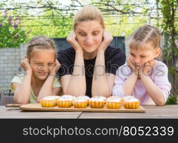 Mother and two daughters with different funny emotion looking at easter cupcakes