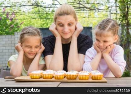 Mother and two daughters with different funny emotion looking at easter cupcakes
