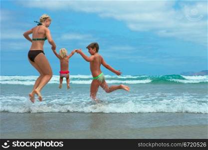 Mother and two kids jumping on beach