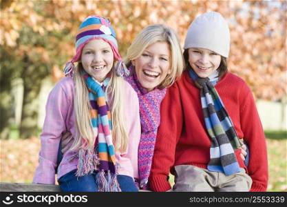 Mother and two young children outdoors in park smiling