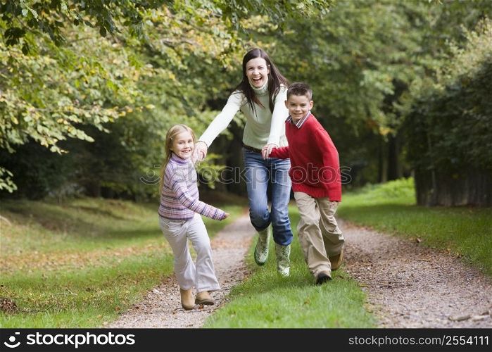 Mother and two young children running on path outdoors (selective focus)