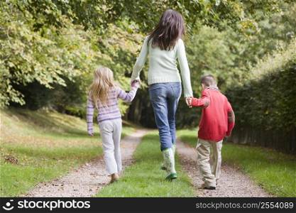 Mother and two young children walking on path outdoors (selective focus)