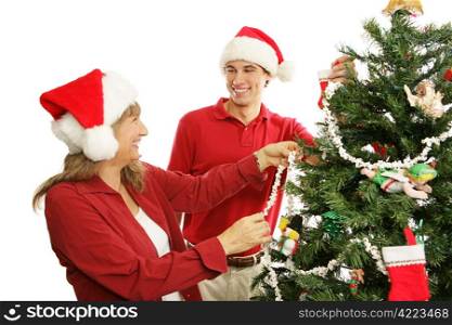 Mother and young adult son have fun decorating the Christmas tree. Isolated on white.