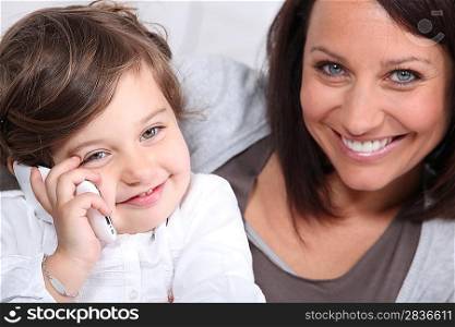 Mother and young daughter making a phone call