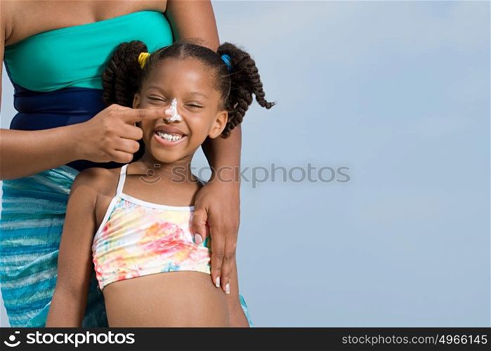 Mother applying suncream to daughters nose