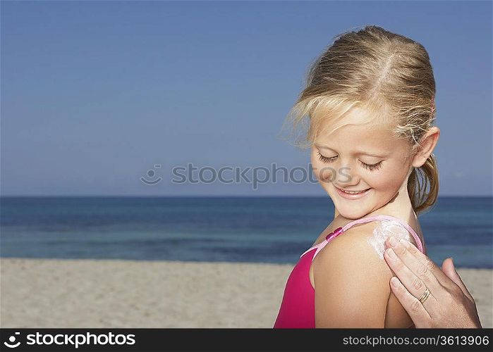 Mother applying sunscreen to daughter (5-6), close-up of hand