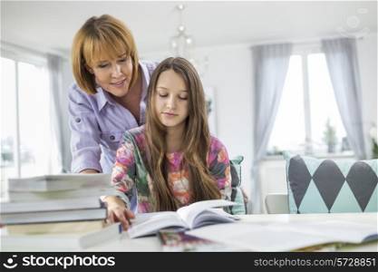 Mother assisting daughter in doing homework at table