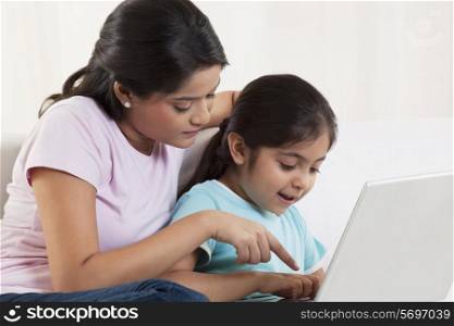 Mother assisting daughter using laptop