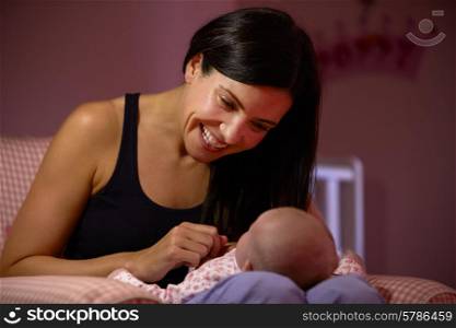 Mother At Home Cuddling Newborn Baby In Nursery