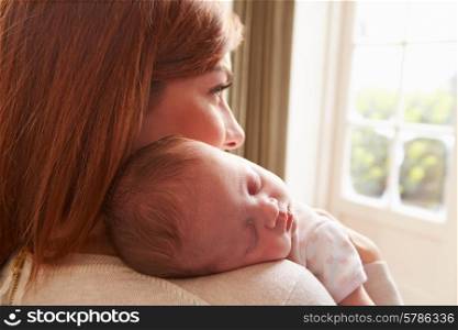 Mother At Home With Sleeping Newborn Baby Daughter