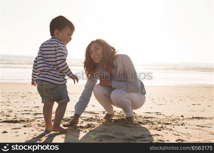 Mother at the beach with her baby. Young mother exploring the beach with her baby