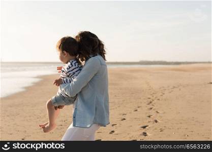 Mother at the beach with toddler. Young mother exploring the beach with toddler