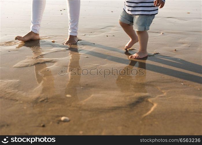 Mother at the beach with toddler. Young mother exploring the beach with toddler