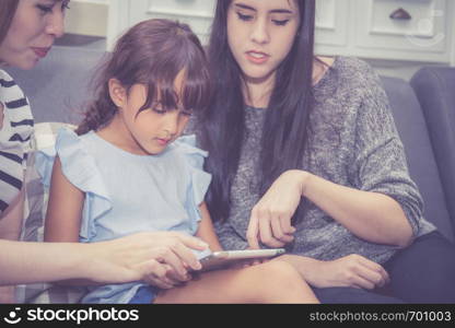 Mother, Aunt and kid having time together lerning with using tablet at home with relax and happy on couch, education and lifestyle concept.