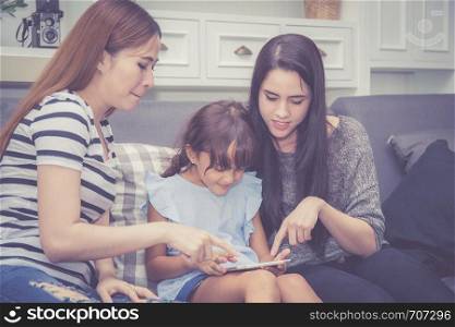 Mother, Aunt and kid having time together lerning with using tablet at home with relax and happy on couch, education and lifestyle concept.
