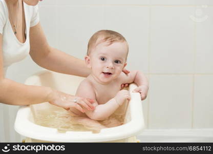 Mother bathing her adorable baby in bathroom