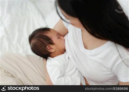 mother breastfeeding newborm baby on a bed