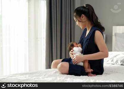 mother breastfeeding newborm baby on a bed