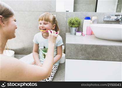 mother brushing teeth daughter