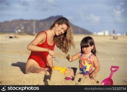 Mother Building Sandcastle With Daughter