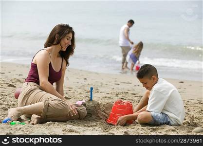 Mother building sandcastles with son on beach