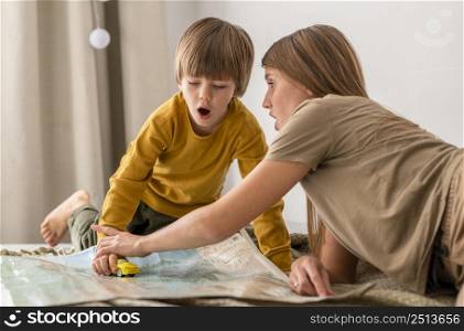 mother child playing together with car figurine map