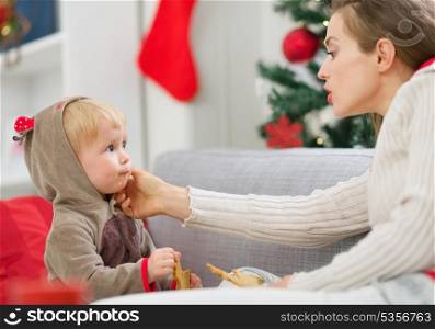 Mother cleaning eat smeared baby eating Christmas cookies