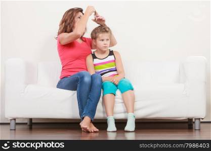 Mother combing daughter, care about hairstyle. Girl is unhappy mom pulling her hair. Important role in child life.