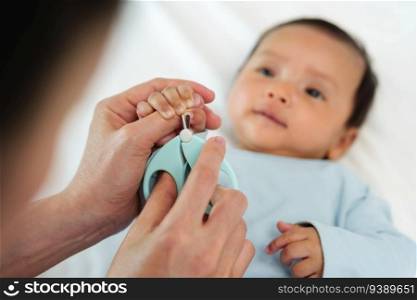 mother cutting newborn baby’s hand fingernails with nail scissors.