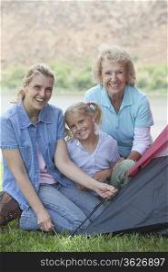 Mother daughter and grand-daughter putting up a tent