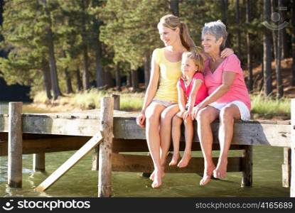 Mother,daughter and grandmother sitting by lake