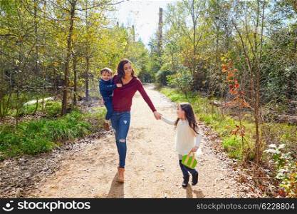 Mother daughter and son family in the park walking in a trail