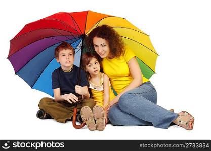 mother, daughter and son with big multicolored umbrella sitting isolated on white and looking at camera