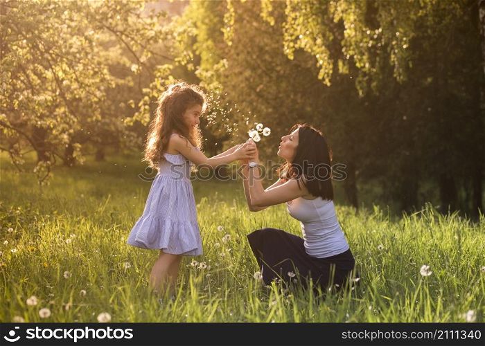 mother daughter blowing dandelion flower park