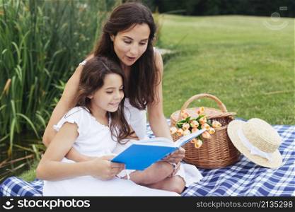 mother daughter reading book picnic