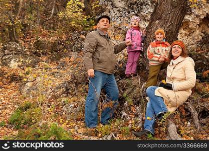 Mother, daughter, son and grandfather in autumnal forest near the tree