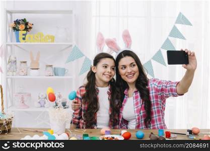 mother daughter with bunny ears taking selfie mobile phone home