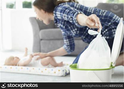 Mother Disposing Of Baby Nappy In Bin