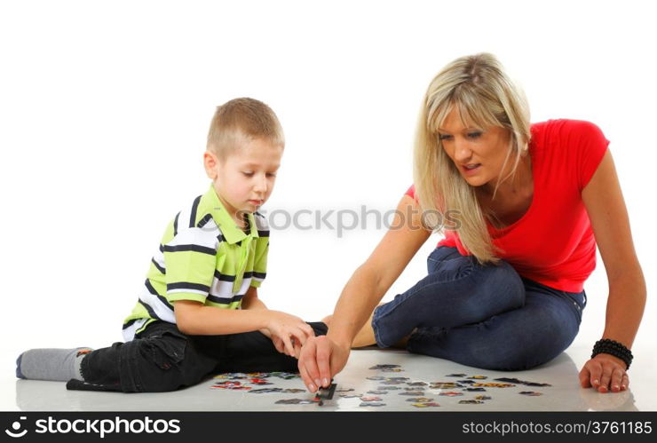 mother doing playing puzzle toy together with her son on floor isolated on white background