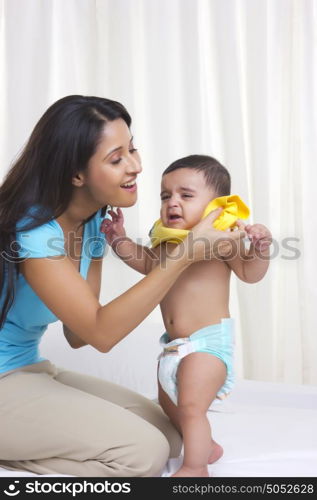 Mother dressing baby