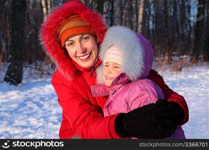 Mother embraces daughter in park in winter