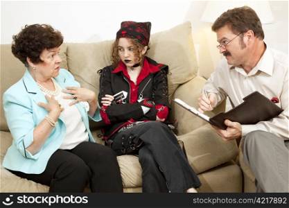 Mother explains herself to a family counselor while her rebellious teen daughter looks on.