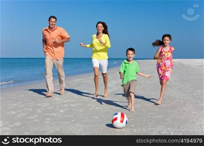 Mother, Father and Children Family Running With Football on Beach