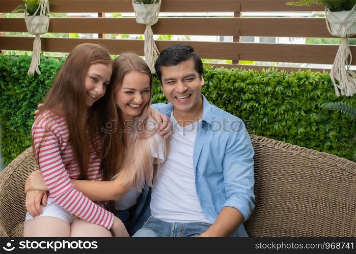 mother, father and daughter sitting on sofa and big smiling together in garden home portrait, young family concept