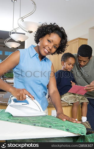 Mother father and son in domestic kitchen, woman ironing