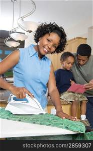Mother father and son in domestic kitchen, woman ironing