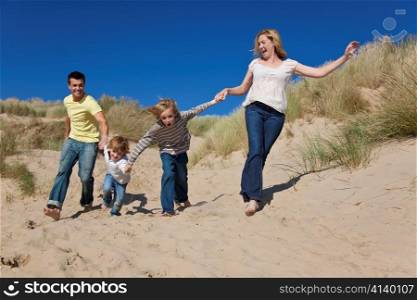 Mother, Father and Two Boys Running Having Fun At Beach