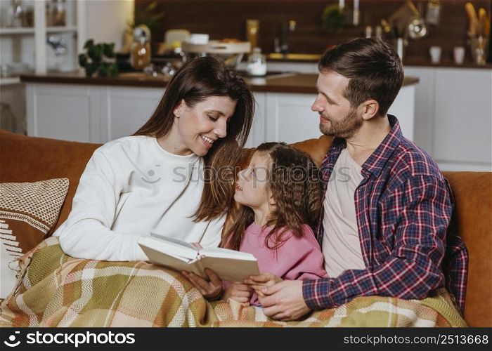 mother father reading book with daughter home